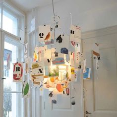 a chandelier made out of various objects hanging from it's sides in front of a window