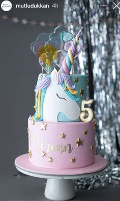 a pink and blue cake with a unicorn on it's top that says 5