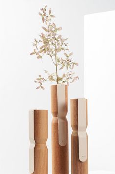 three wooden vases with flowers in them sitting on a white surface next to each other