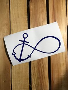 a sticker with an anchor on it sitting on top of a wooden table next to a fence