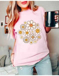 Step into the warmth of style and embrace the carefree vibes with our "Daisy Days Sunshine Bloom Tee." This delightful t-shirt is a celebration of the spirit of warmer days and sunny moments. Crafted from soft, breathable cotton, it provides comfort that matches its sunny disposition. The cheerful design features a vibrant daisy in full bloom, symbolizing the positivity and brightness that comes with the arrival of warmer weather. The playful colors and lively imagery make it a perfect addition Trendy Smiley Face Summer Tops, Cute Spring Tops With Smiley Face, Cute Smiley Face Tops For Spring, Cute Smiley Face Top For Spring, Smiley Face Top For Loungewear, Relaxed Fit Smiley Face Top For Loungewear, Spring Smiley Face Crew Neck Top, Spring Crew Neck Top With Smiley Face, Cute Smiley Face Tops For Summer