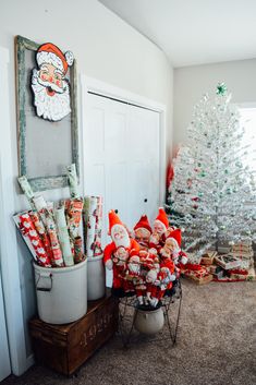 a white christmas tree sitting next to a bucket filled with candy canes and santa clause decorations