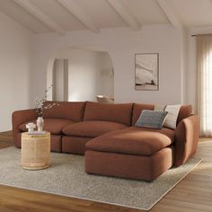 a large sectional couch sitting on top of a wooden floor next to a table with a vase