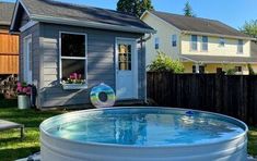 an above ground pool in the backyard with grass and flowers on the lawn next to it