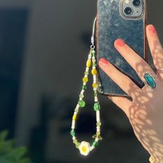 a woman's hand holding up a cell phone with a chain attached to it