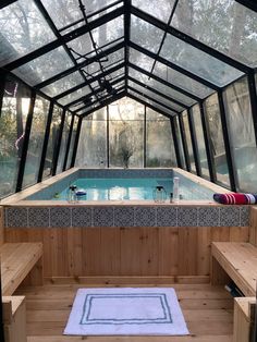 an indoor swimming pool in the middle of a wooden floored area with glass walls