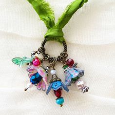 a close up of a key chain with charms on it and a green ribbon around the neck