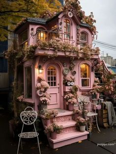 a pink doll house with lots of flowers on the front and stairs to the second floor