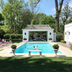 a pool with a bench in front of it and people sitting on chairs around the pool