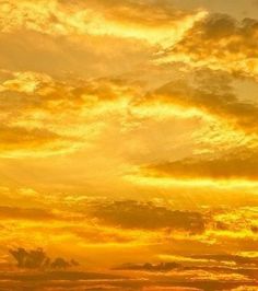 an airplane is flying in the sky with orange and yellow clouds above it at sunset