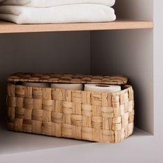 two wicker baskets sit on top of shelves next to folded towels and folded cloths