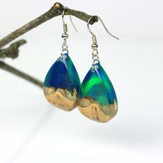 "These unique teardrop earrings are made using lab-created opal, resin and precious burl wood. The iridescent opal makes it appear as if there is a tiny galaxy stuck inside. The resin has glass like properties and is polished to a high gloss finish - it is made to stun. The earrings are unique, and it is impossible to make another piece exactly like them. The earrings come presented in a black modern jewelry box, perfect for gifting! We can also add a gift message, just let us know in \"note to Teardrop Resin Jewelry, Resin Teardrop Earrings For Gifts, Unique Teardrop Resin Earrings, Unique Hypoallergenic Teardrop Earrings, Modern Jewelry Box, Pendulum Earrings, Opal Drop Earrings, Original Jewelry Design, Unique Opal