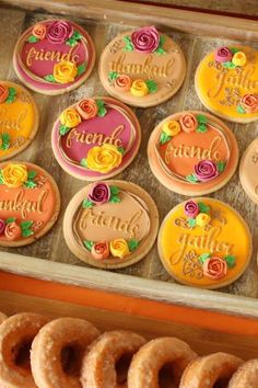 decorated cookies and pastries in a box on a table with oranges, yellows and pinks