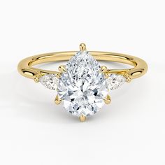 a yellow gold engagement ring with two pear shaped diamonds on the side and an oval center stone