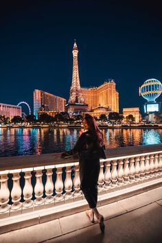 a woman standing next to the eiffel tower at night