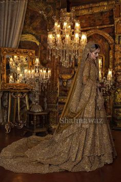 a woman in a gold wedding dress standing next to a chandelier