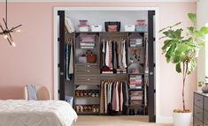 a bedroom with pink walls and an open closet in the middle, filled with clothes