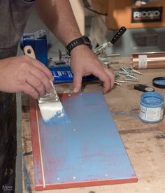 a man is using a brush to paint the side of a piece of blue wood