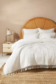 the bed is made up with white linens and pillows on it, along with a wooden headboard