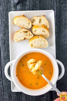 a bowl of soup with bread on the side and a spoon in it, ready to be eaten