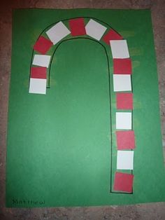 the paper is cut out to look like a candy cane on a green board with red and white strips