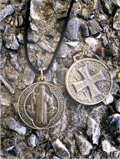 two necklaces with an image of the virgin mary and jesus on them sitting on some rocks