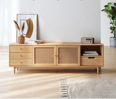 a living room with a wooden entertainment center and plants on the sideboard next to it