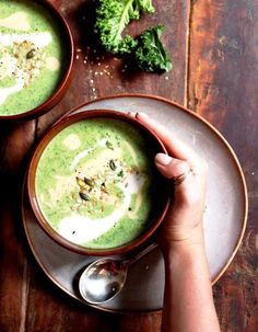 two bowls of broccoli soup on a wooden table