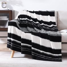 a black and white blanket sitting on top of a couch next to a wooden table