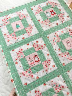 a green and white quilt with red flowers on the bottom is sitting on a table