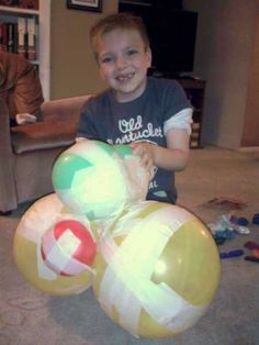 a young boy is sitting on the floor with three large balls in front of him