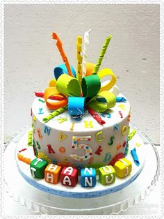 a birthday cake with colorful candles and letters on the top is sitting on a plate