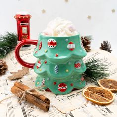 a green ceramic christmas tree mug sitting on top of a table next to orange slices