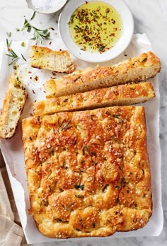 bread and other food items on a white tablecloth with napkins, salt and pepper sprinkles