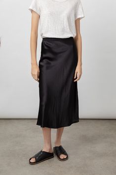 DETAILS | Super smooth, satin crepe, high-rise, unlined, sleek black midi skirt featuring black exposed elastic waistband, swingy fit, and flattering bias cut. Made with luxurious fabric in an easy pullover silhouette, this swingy skirt is perfect for work or play. 55% Rayon | 45% Viscose. Imported. CARE | Dry Clean Only. FIT | Recommend ordering true to size. Skirt Length: 31 1/2" (Measured from Small) Model is wearing size S.Model’s Measurements: Height 5’10“, Bust 32", Waist 24", Hips 34" Black Satin Midi Skirt, Crepe Skirts, Elegant Drapes, Satin Midi Skirt, Luxurious Fabric, Slip Skirt, Minimal Chic, Black Midi Skirt, Black Midi