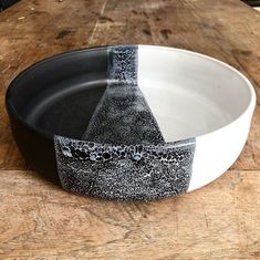 a black and white plate sitting on top of a wooden table next to a bowl