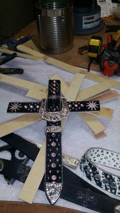 a cross made out of strips of paper and other crafting supplies on a table