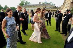 two women in evening gowns and men in tuxedos are talking to each other