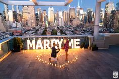 two people standing on top of a roof with candles in the shape of a heart