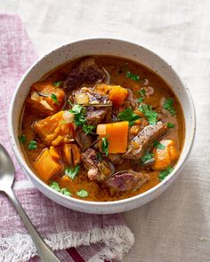 a bowl of stew with meat, carrots and parsley