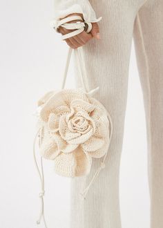 a woman holding a white purse with a flower on it