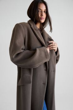 Elevate your wardrobe with the timeless Harper Maxi Wool Coat. This oversized silhouette is crafted with 100% soft wool detailed with double-breasted closures, chest welt pockets, front flap pockets, a back vent, side pockets, and elongated slouchy sleeves. Fully lined for maximum warmth. Oversized Classic Long Blazer, Classic Oversized Solid Pea Coat, Oversized Wool Coat With Notch Lapel, Classic Oversized Outerwear For Business, Timeless Fall Outerwear With Pockets, Timeless Outerwear With Pockets For Fall, Classic Oversized Single-breasted Outerwear, Classic Oversized Single Breasted Outerwear, Classic Oversized Outerwear