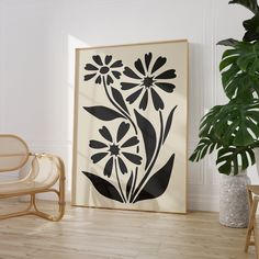 a black and white flower print on a wall next to a chair with a plant in the corner