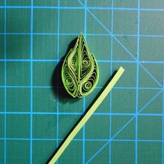 a green piece of paper sitting on top of a cutting board next to a ruler