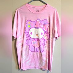 a pink hello kitty t - shirt hanging on a wall