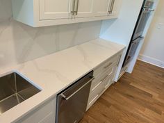 a white kitchen with marble counter tops and stainless steel dishwasher in the center