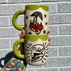 a person holding two coffee mugs with designs on them