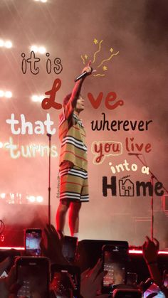 a man standing on top of a stage with his arms in the air while holding a microphone