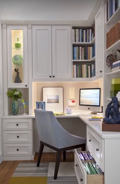 a home office with white cabinets and desk