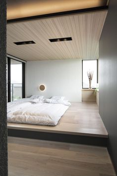 a large bed sitting on top of a wooden floor next to a tall window in a bedroom